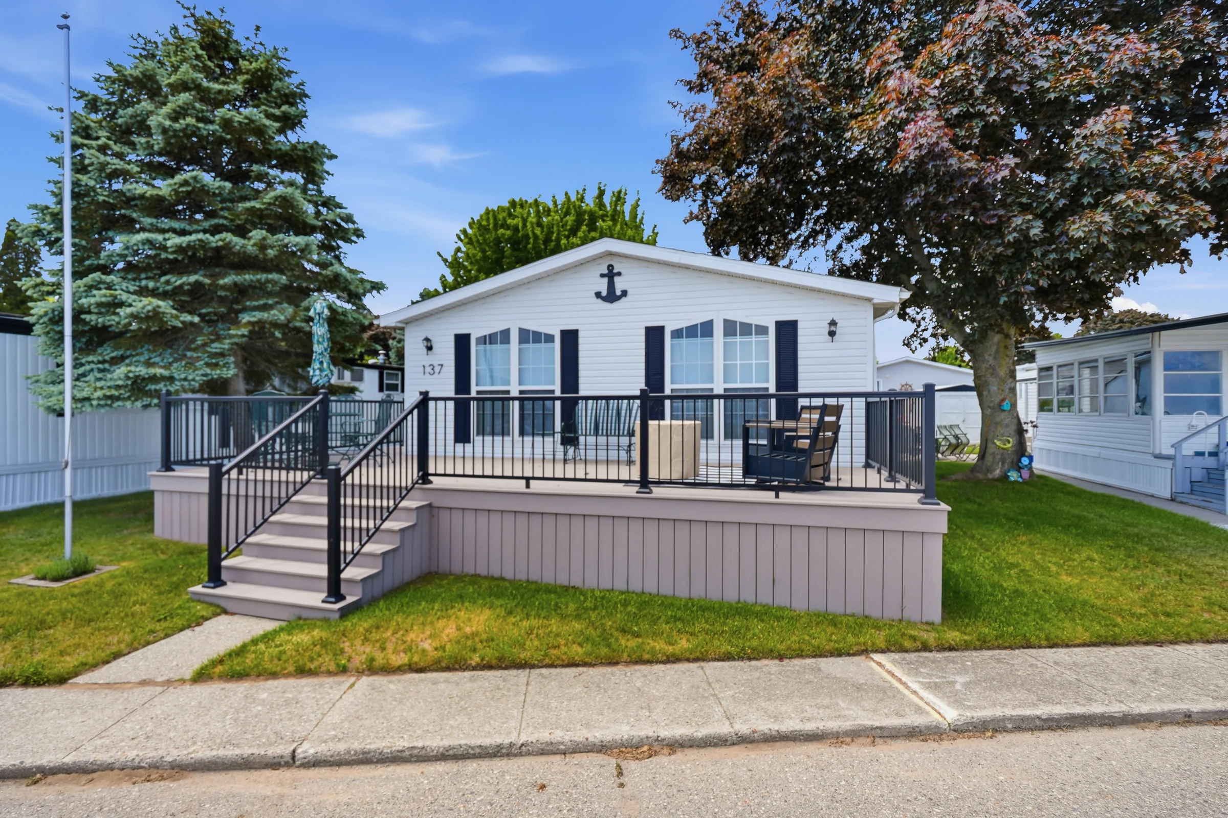Well-maintained manufactured home with a large front deck at Huron Shores